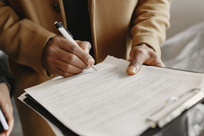 A person filling out forms with a pen, representing the paperwork required during travel